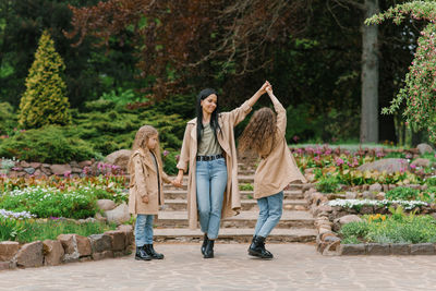 Caucasian schoolgirl daughters walk with their mother in spring in a blooming park