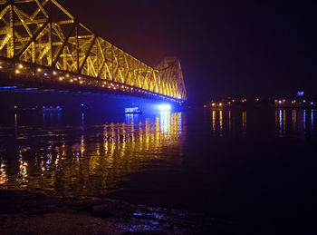 Illuminated bridge over river at night