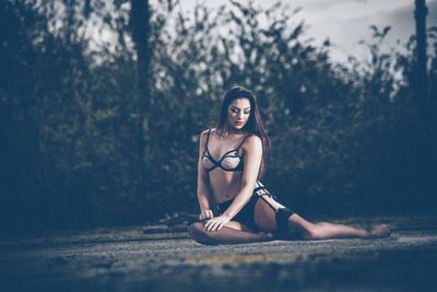 Portrait of young woman in bikini against trees