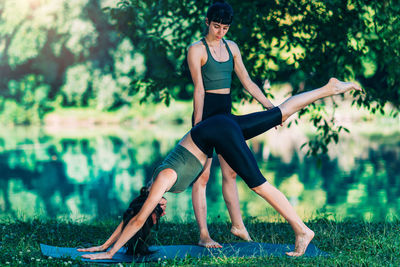 Women doing yoga by the water. instructor helping and teaching yoga.