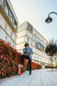 Low angle view of woman standing by building against sky