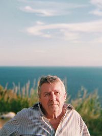 Close-up of man looking away while standing against sky