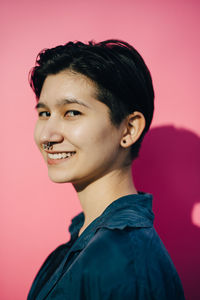 Portrait of smiling young woman against pink background