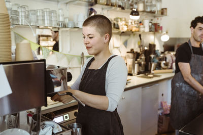 Young female barista preparing coffee at cafe