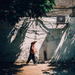 Full length of woman walking by wall