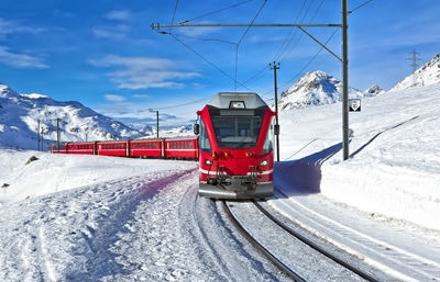 Train on railroad track by snowcapped mountains against sky