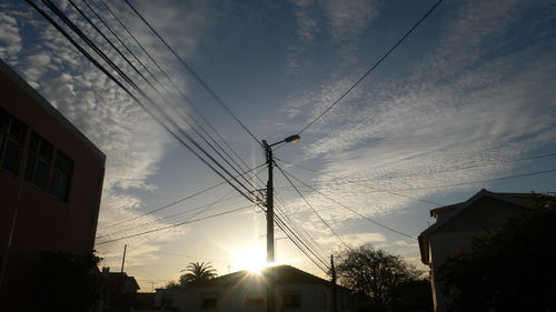 Low angle view of electricity pylon against cloudy sky