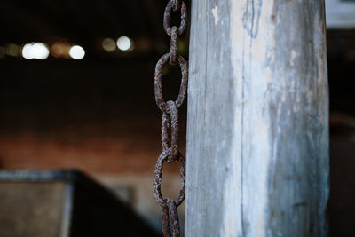 Close-up of chain hanging by wooden pole