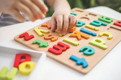 Cropped hand playing with toy blocks on table