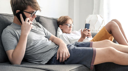 Young woman using phone while sitting on sofa at home