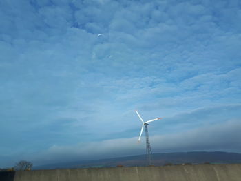 Wind turbines on field against sky