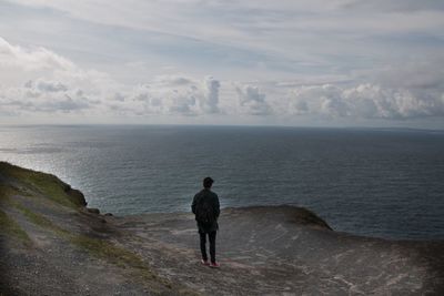 Rear view of a man overlooking calm sea