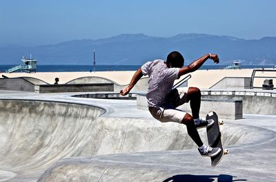 Full length of man skateboarding in park against clear sky at beach