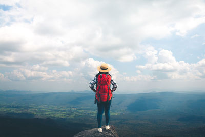 Rear view of man standing on mountain against sky