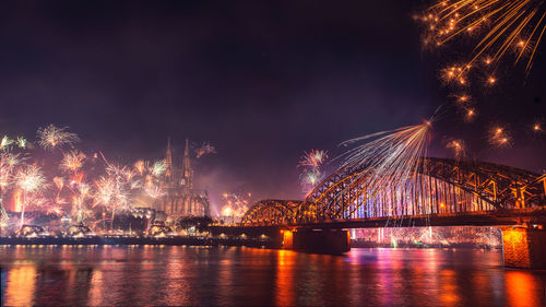 Firework display over river against sky at night