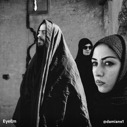 Portrait of young woman standing against wall