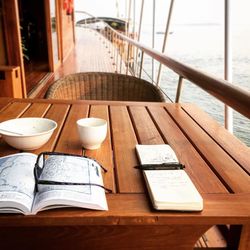 Pen and book with empty bowls on wooden table in boat