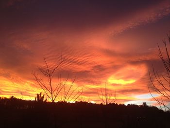 Silhouette landscape against cloudy sky during sunset