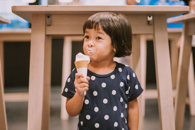 Cute girl eating ice cream while looking away