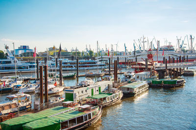 Boats moored at harbor against sky in city