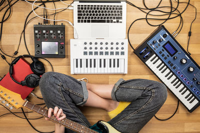 Low section of woman playing guitar while sitting on floor