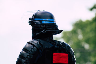 Rear view of mature man wearing helmet against clear sky