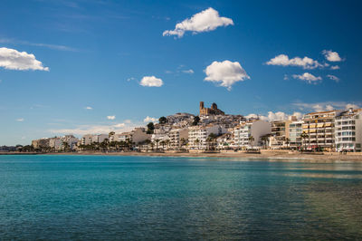 City at waterfront against cloudy sky