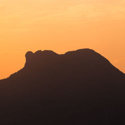 Scenic view of silhouette mountains against orange sky