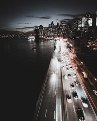 High angle view of cars moving by river on road in city at night