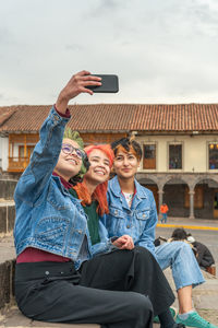 Female friends taking selfie photo on mobile phone while resting in city of cusco