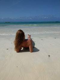 Rear view of bikini woman relaxing at sandy beach