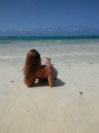 Rear view of woman sitting on beach