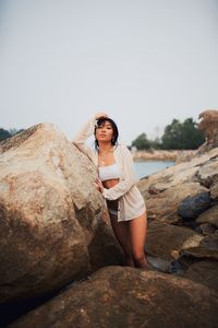 Woman standing on rock against clear sky