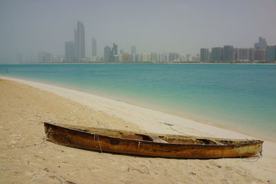 View of boat on beach against urban skyline