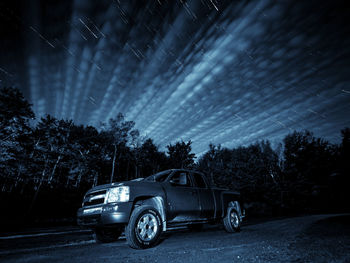 Car against illuminated trees at night