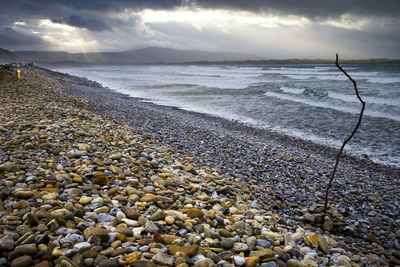 Beach with stormy seas and dark clouds and a ray of sunshine at strandhill beach, sligo, ireland