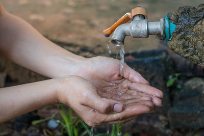 Cropped hands of woman drinking water