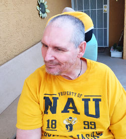 Portrait of mature man standing against yellow wall