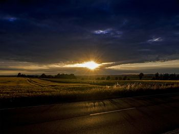 Scenic view of landscape against cloudy sky at sunset