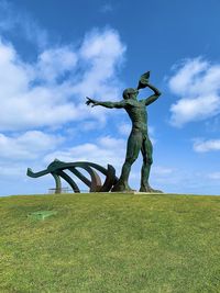 Statue on field against sky