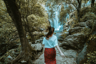 Rear view of woman standing in forest