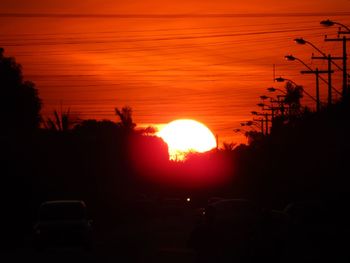 Silhouette car against orange sky during sunset