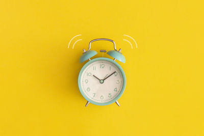 Close-up of alarm clock against yellow background
