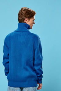 Rear view of man standing against blue background