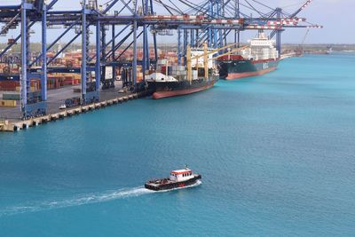 Small tugboat in harbour with large container ships in background