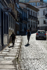 Rear view of people walking on street in city