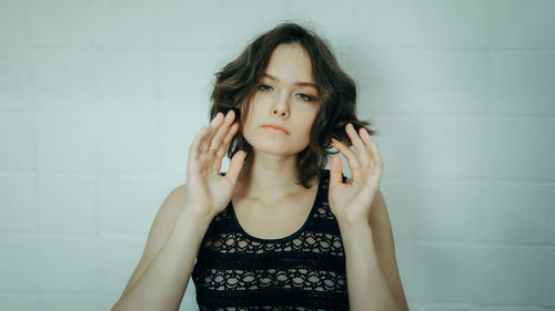 Portrait of young woman standing against wall