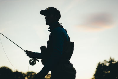 Silhouette of fly-fisherman during evening light