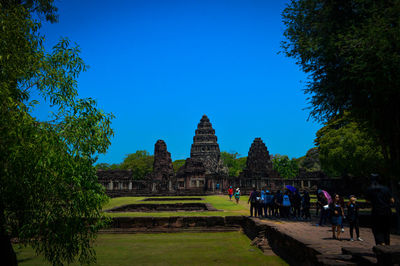 People at temple against clear blue sky