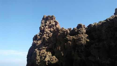 Low angle view of rock formation against clear blue sky